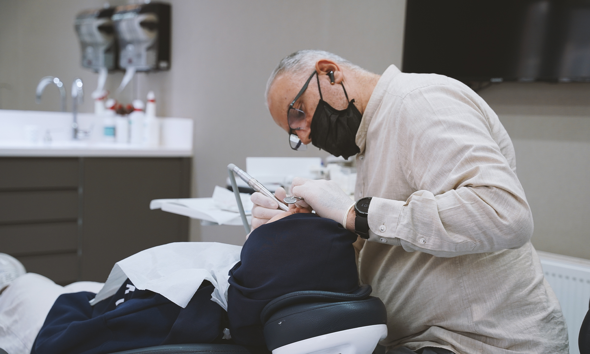 طبيب عيادة عادل للأسنان يفحص مريضاً بمعدات أسنان متطورة